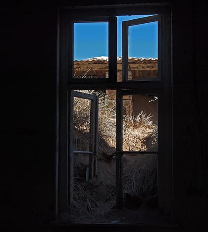 Dunkles Fenster mit Blick auf Wüste und Himmel