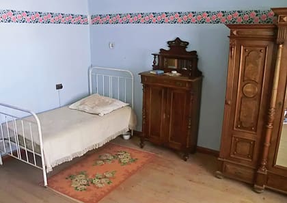 Schlafzimmer mit Eisenbett und Kleiderschrank im Museum