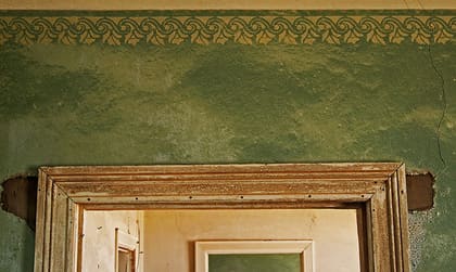 Grün gestrichene Wand mit Schablonenbordüre und Sand