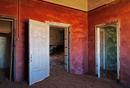 Rot gestrichener Raum mit offener Tür und Sand