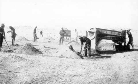 Arbeiter suchen mit bloßen Händen im Sand nach Diamanten