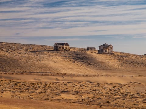 Zwei Häuser von Kolmanskop in der Ferne in der Wüstenlandschaft